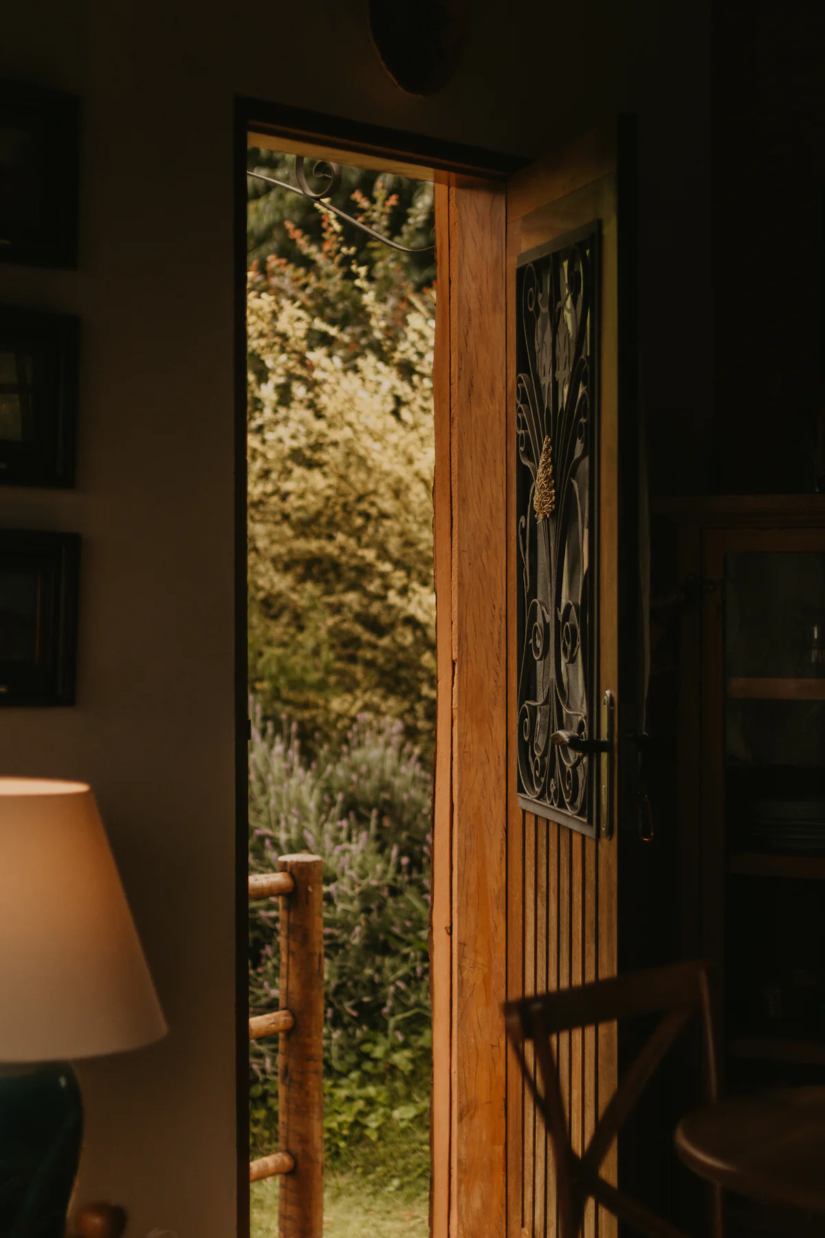 A warm wooden door standing open to a green hillside, a soft lamp glowing beside it